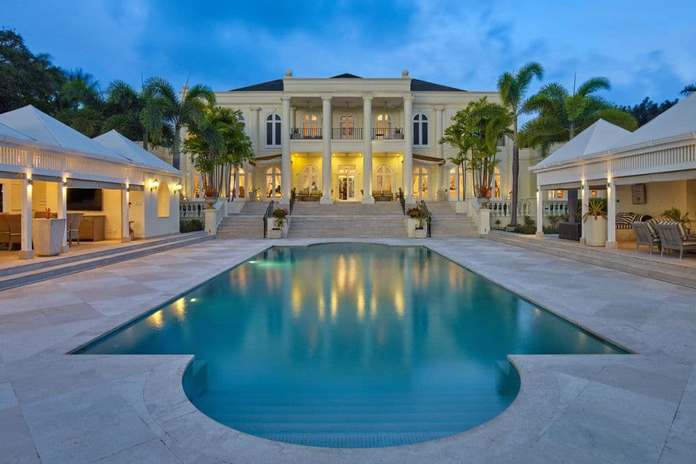The Ridge, a floodlit neo-classical mansion above a large pool at dusk in St Peter, Barbados