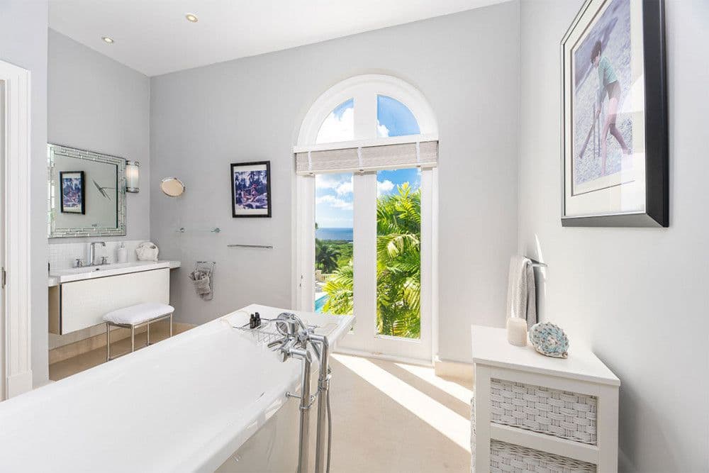 Master en-suite with a freestanding tub beneath an arched window at The Ridge