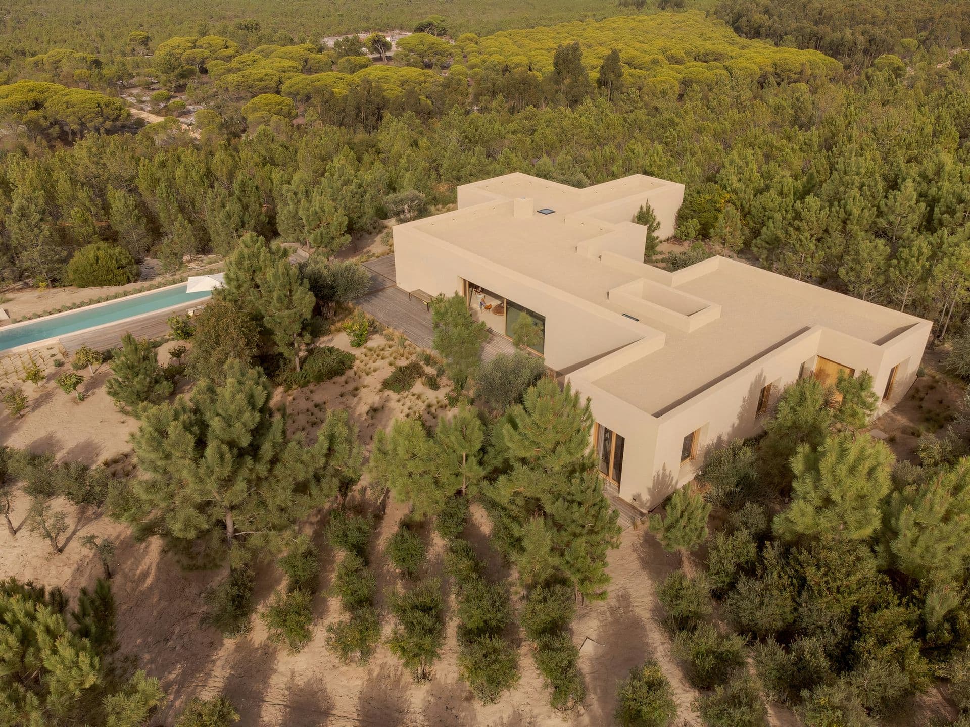 Aerial view of the sand-coloured villa and pool set in pine forest at Mighty Pine