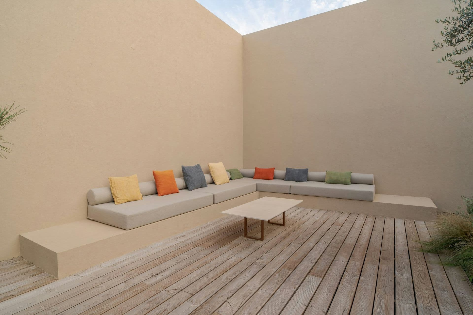 Sheltered courtyard with a built-in sofa and colourful cushions at Mighty Pine