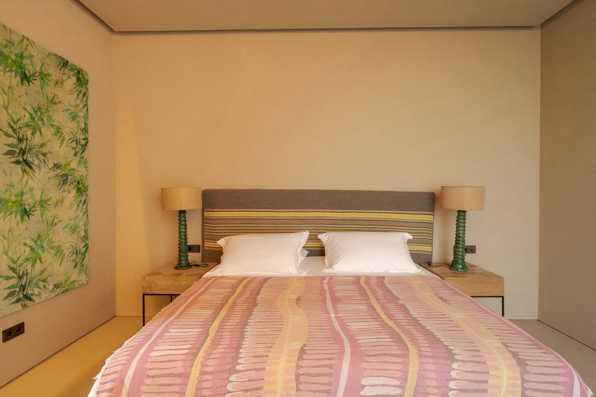 Double bedroom in warm ochre plaster with a striped throw at Mighty Pine