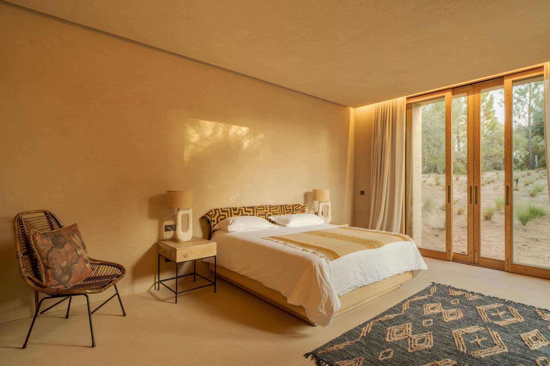 Bedroom with a rattan chair and doors to the pine garden at Mighty Pine