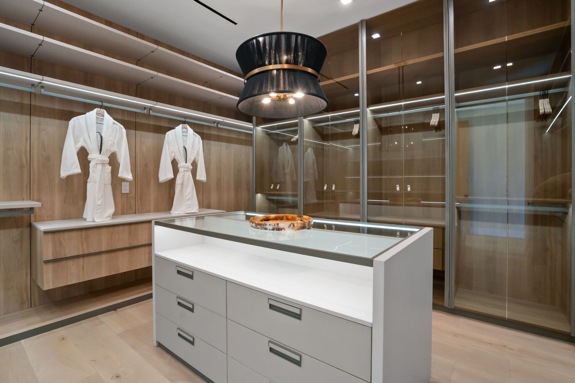 Walk-in dressing room with glass wardrobes and a central island at Bel-Air Oasis, Los Angeles