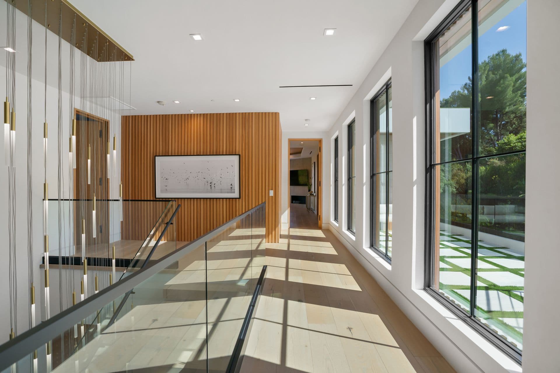 Upper gallery landing with a glass balustrade and clerestory windows at Bel-Air Oasis, Los Angeles