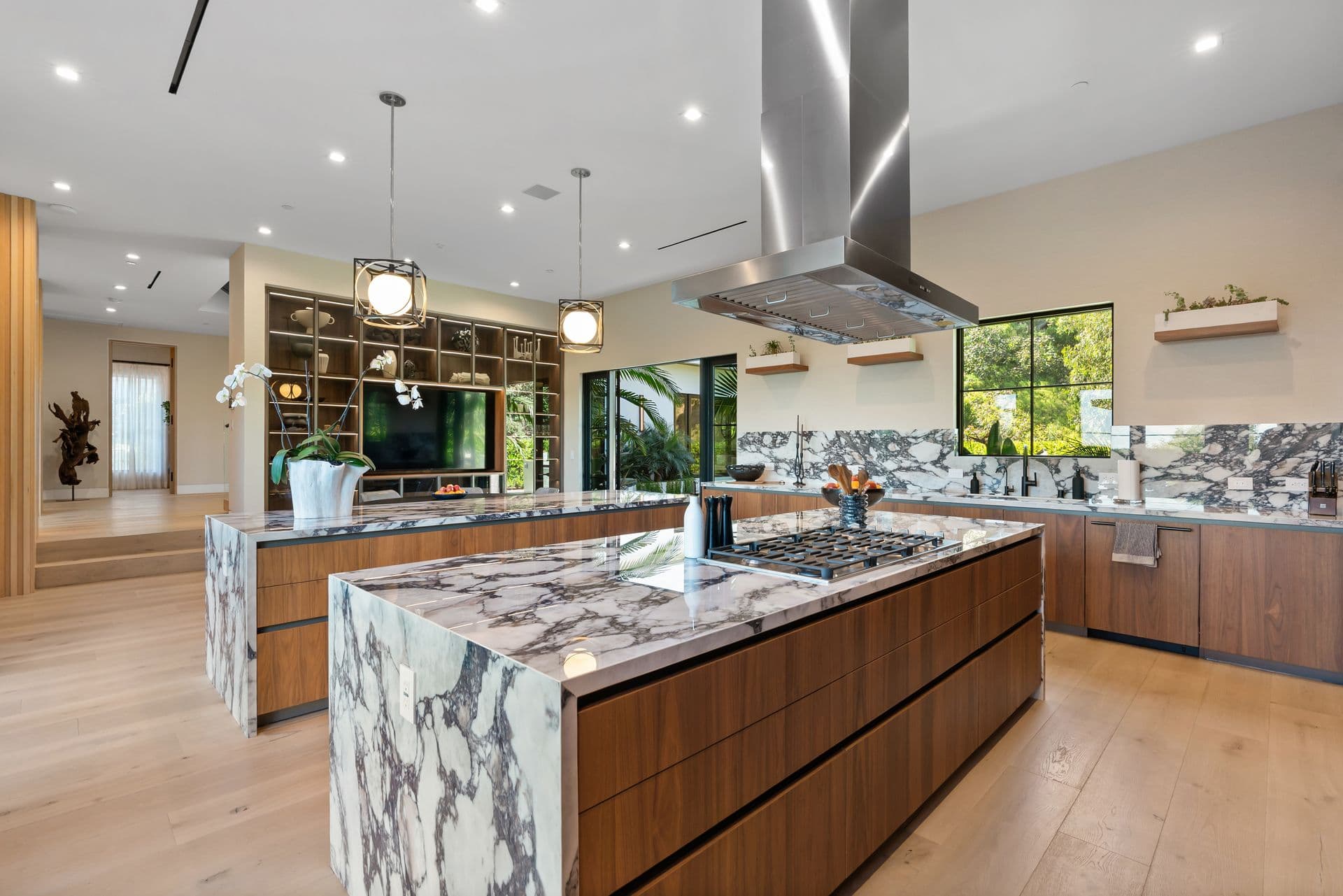Kitchen with a veined-marble island, range and walnut units at Bel-Air Oasis, Los Angeles