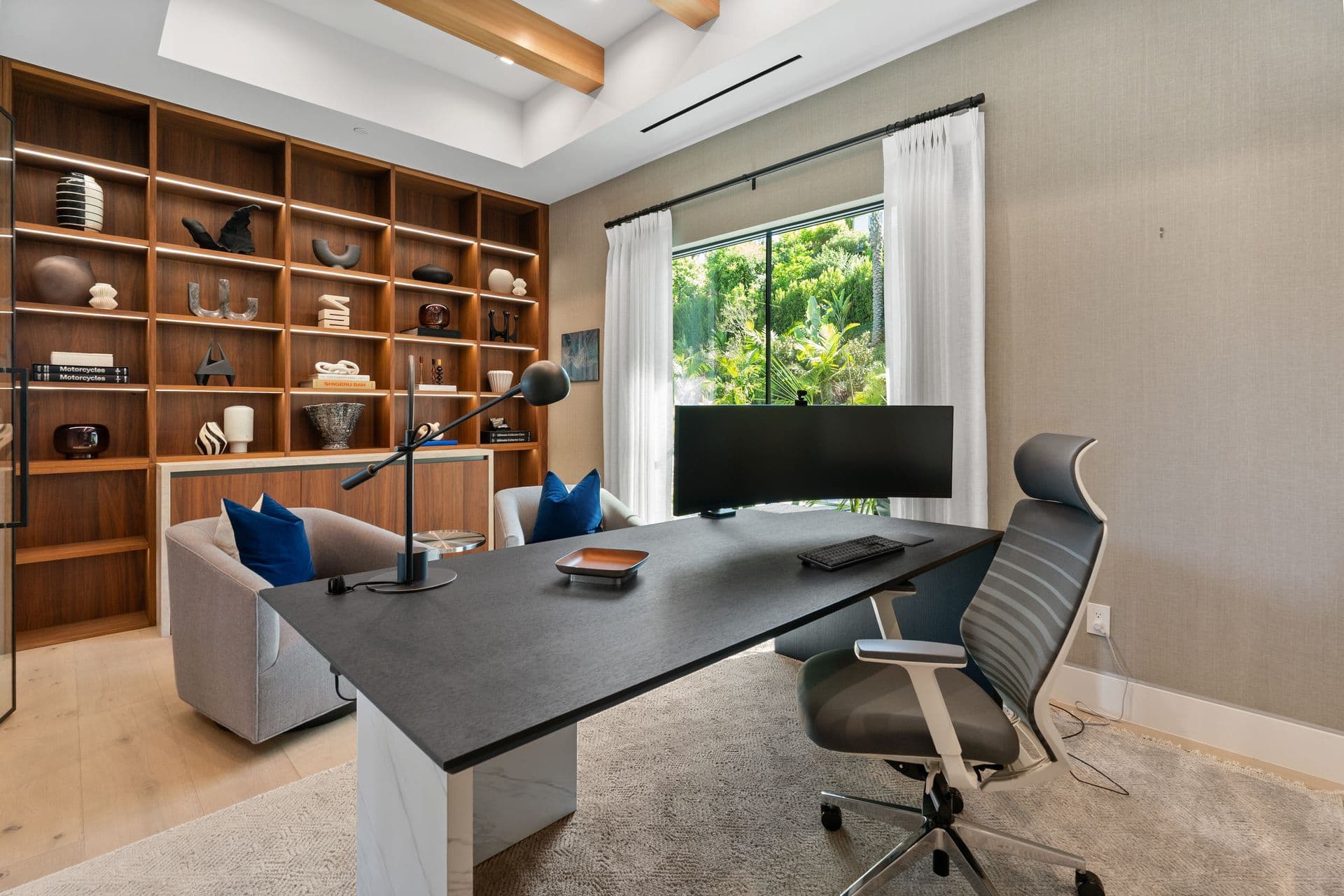 Home office with built-in timber shelving and a curved monitor at Bel-Air Oasis, Los Angeles