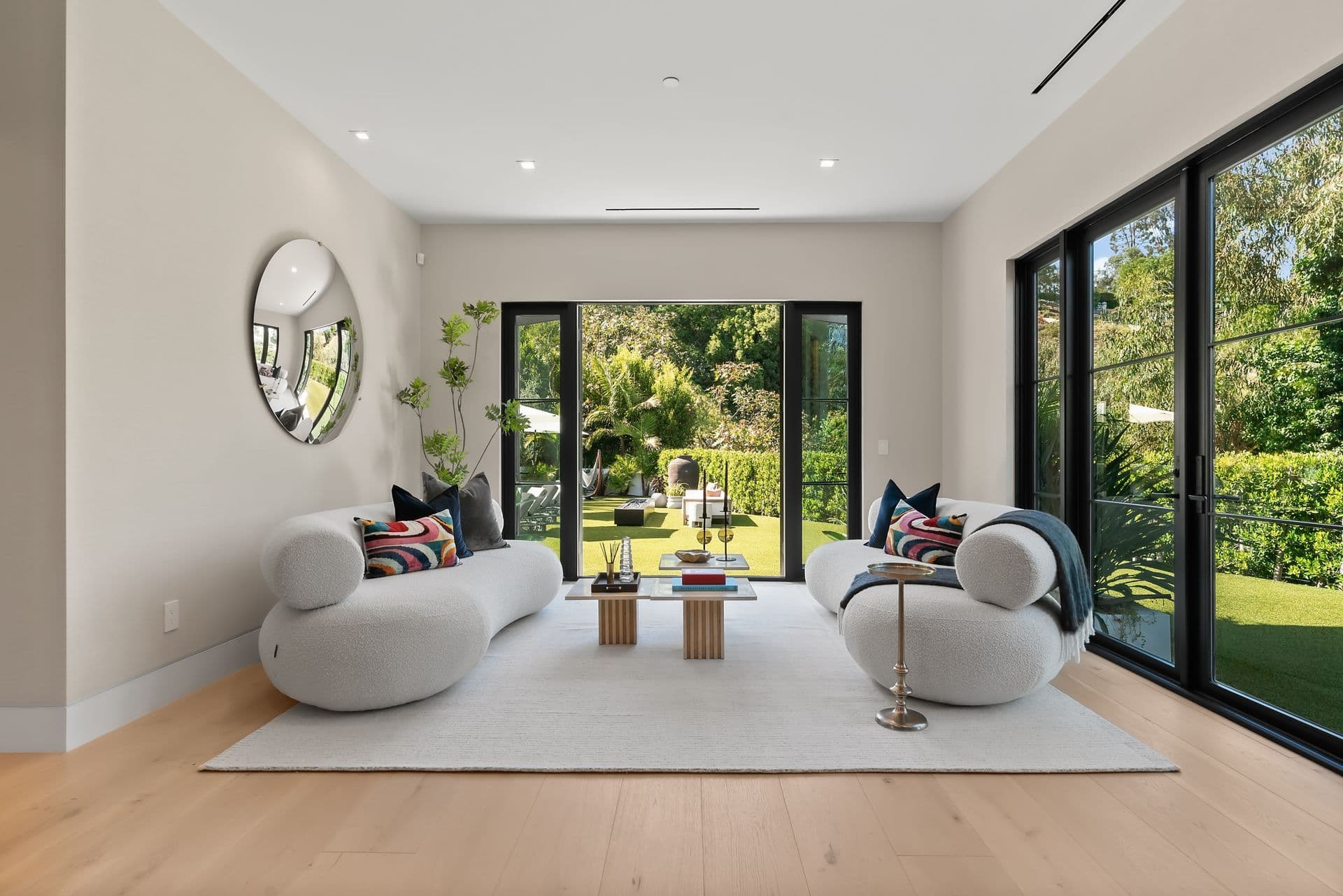 Sitting room with curved cream sofas opening to the garden at Bel-Air Oasis, Los Angeles