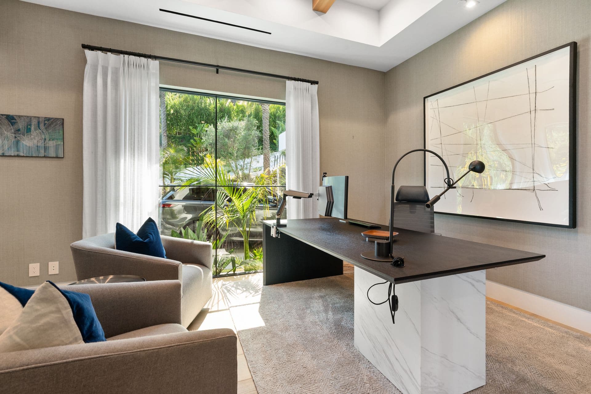 Study with a marble desk and abstract artwork by a garden window at Bel-Air Oasis, Los Angeles