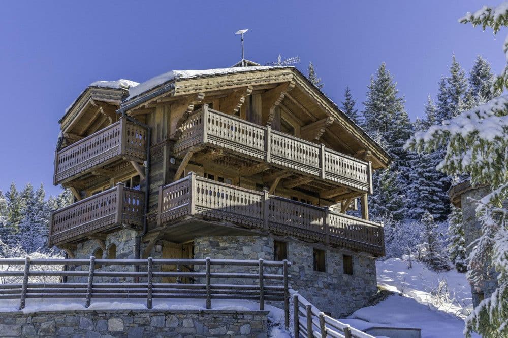 Timber and stone chalet with balconies under snow in Courchevel 1850
