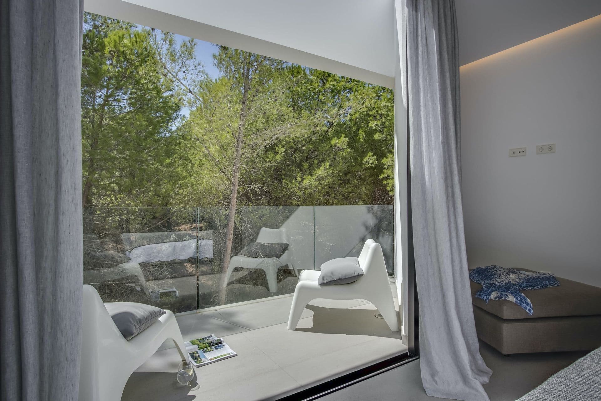 Bedroom suite with a full glass wall opening to a terrace at Dancing Shadows, Ibiza