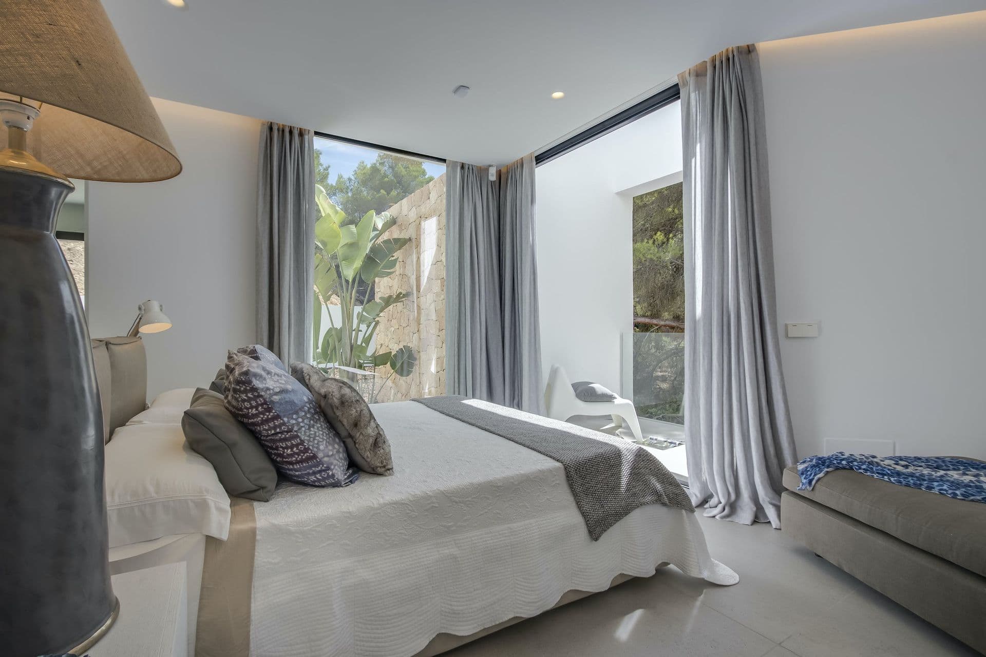 Grey and white double bedroom opening to a terrace with hill views at Dancing Shadows, Ibiza