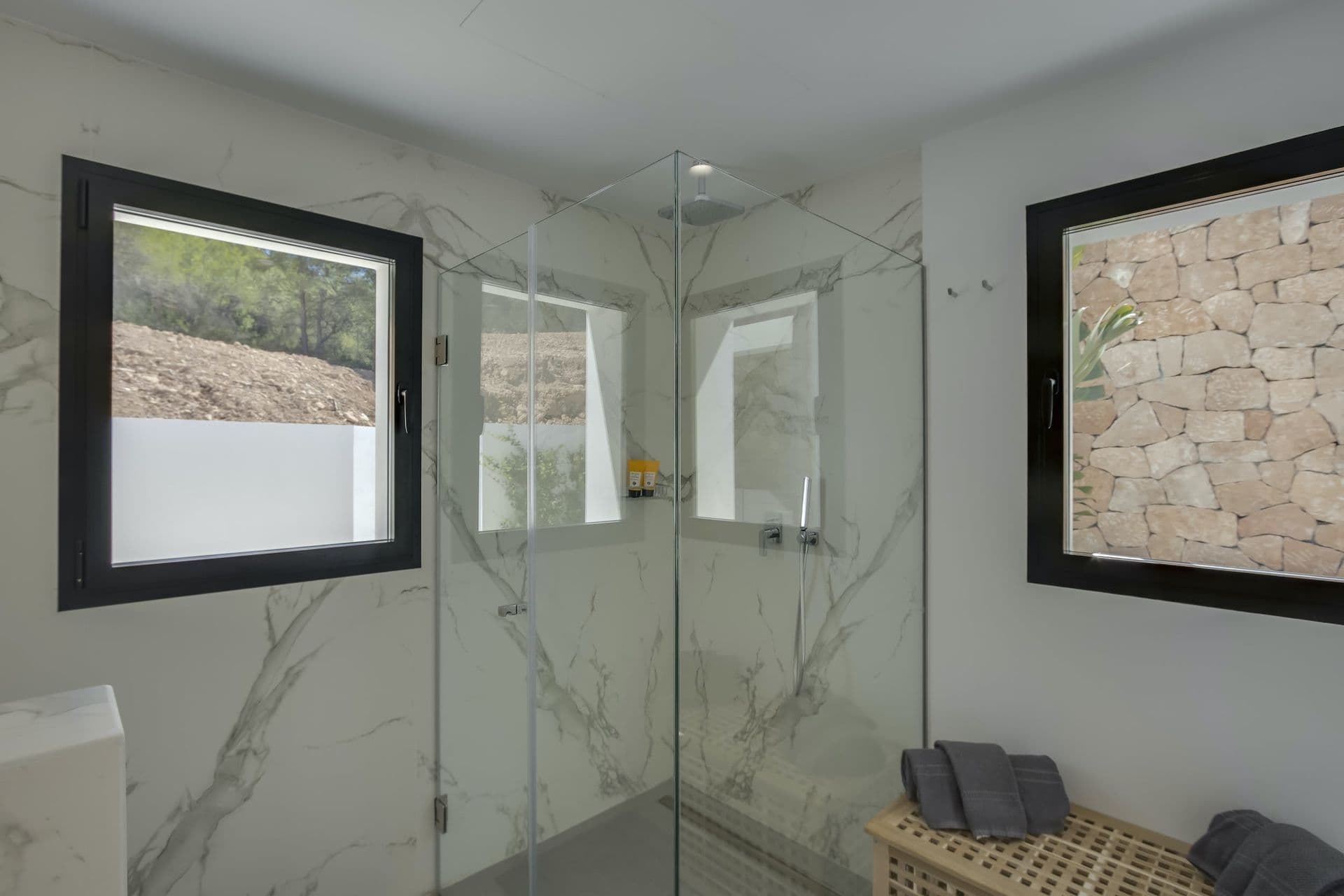 Marble en-suite with a walk-in shower beside a stone feature wall at Dancing Shadows, Ibiza