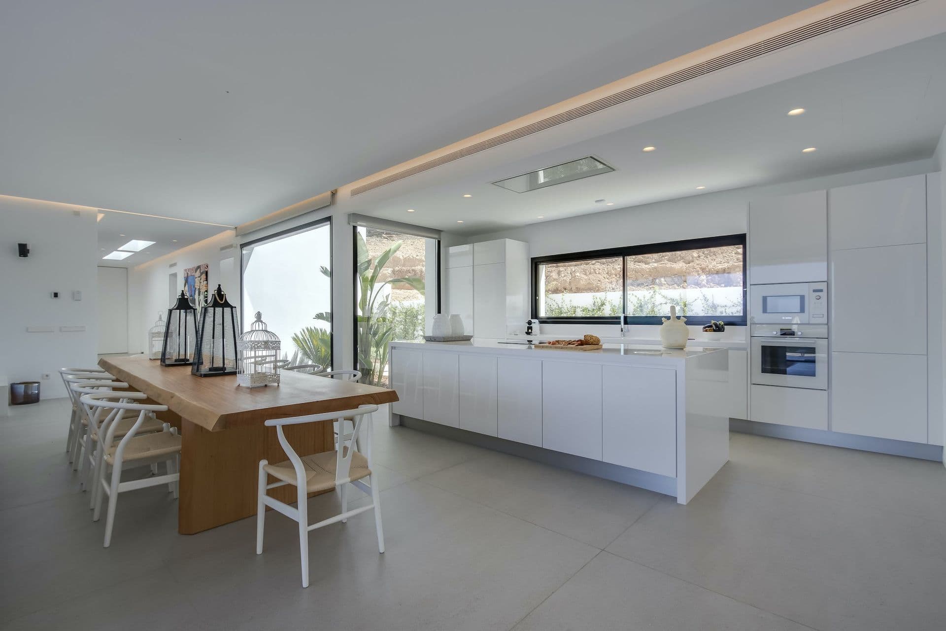 Timber dining table beside a white kitchen island at Dancing Shadows, Ibiza