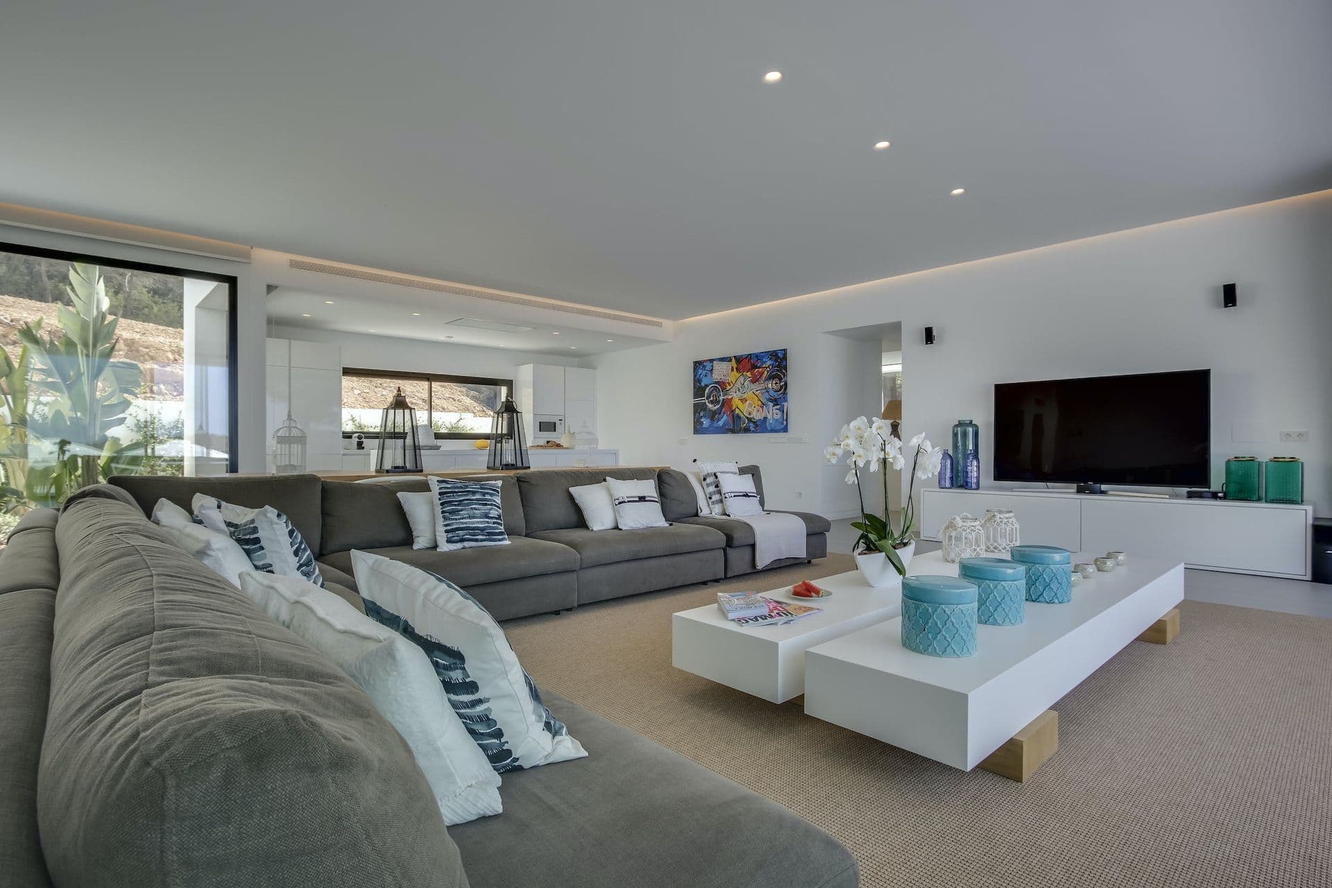 Living room with a grey sofa, television and pop art in a white open-plan space at Dancing Shadows, Ibiza