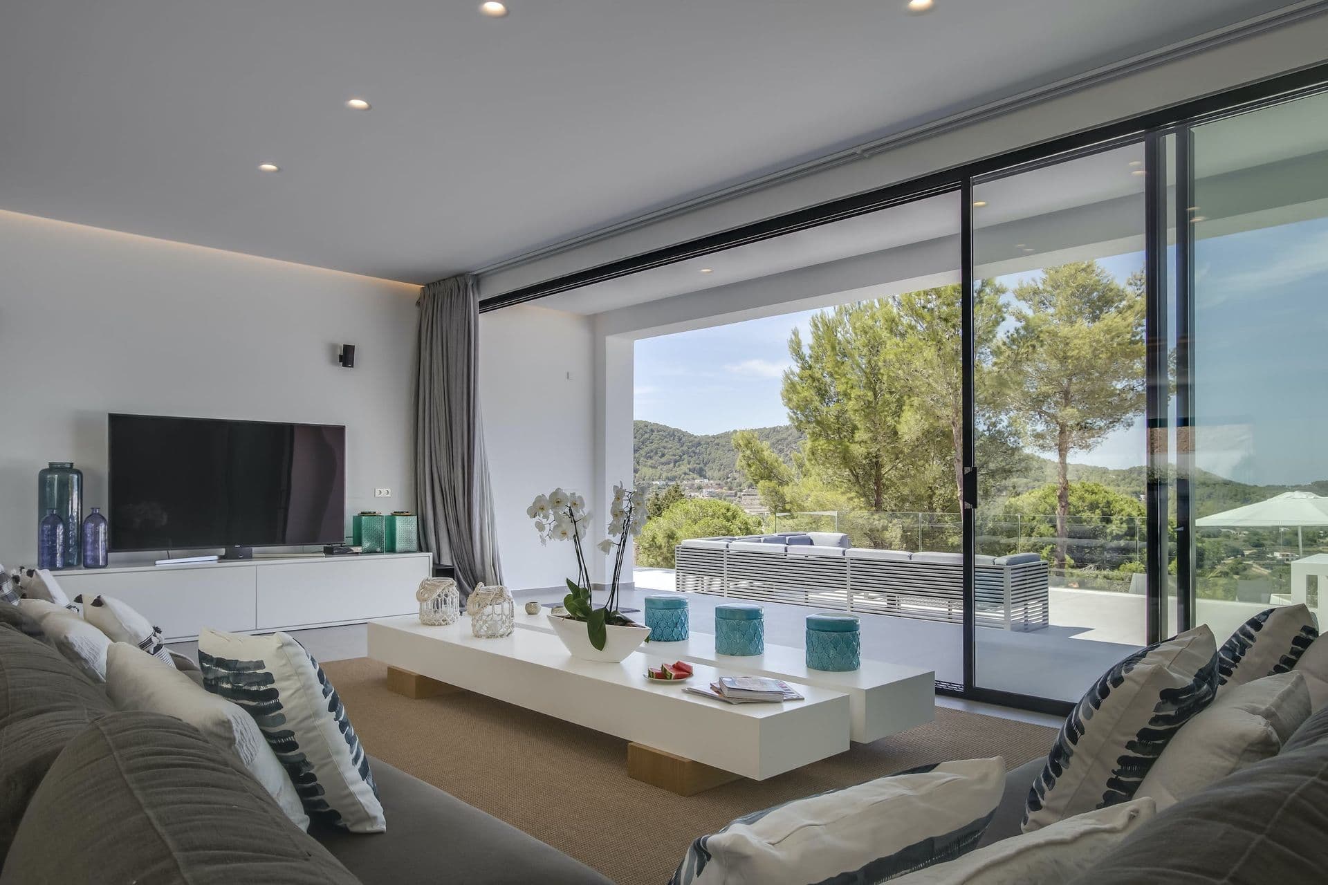 Living area with a grey sofa and sliding glass onto the pool terrace at Dancing Shadows, Ibiza