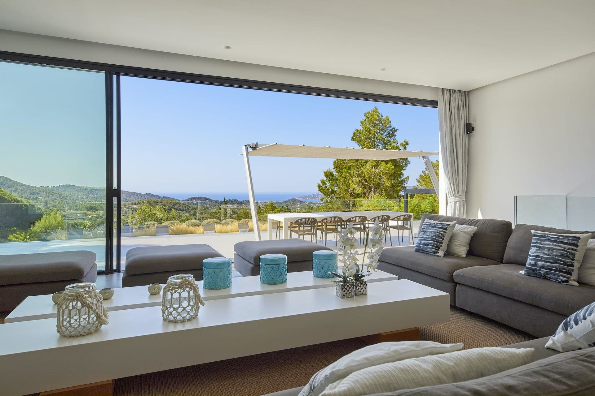 Covered terrace with a lounge and dining set overlooking the hills at Dancing Shadows, Ibiza