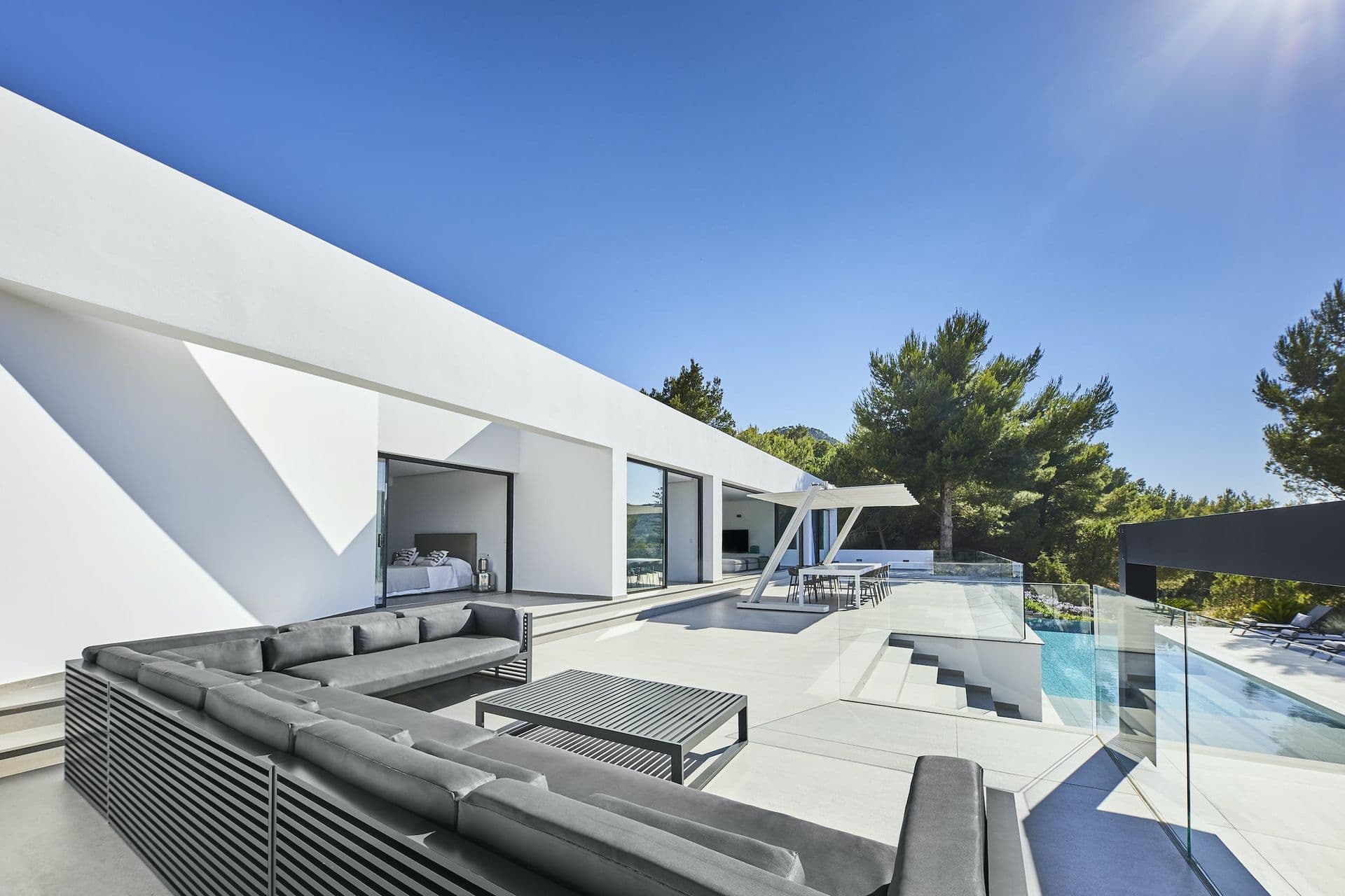 Angular white villa with a pool and terrace lounge among pines at Dancing Shadows, Ibiza