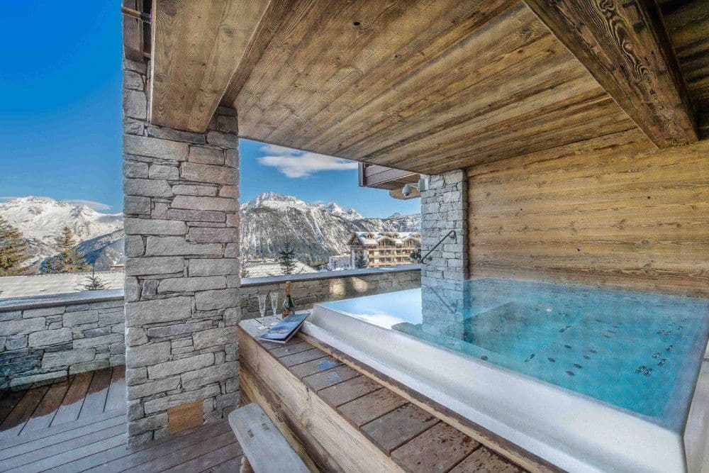 Outdoor hot tub on a stone terrace with mountain views at Courchevel 17