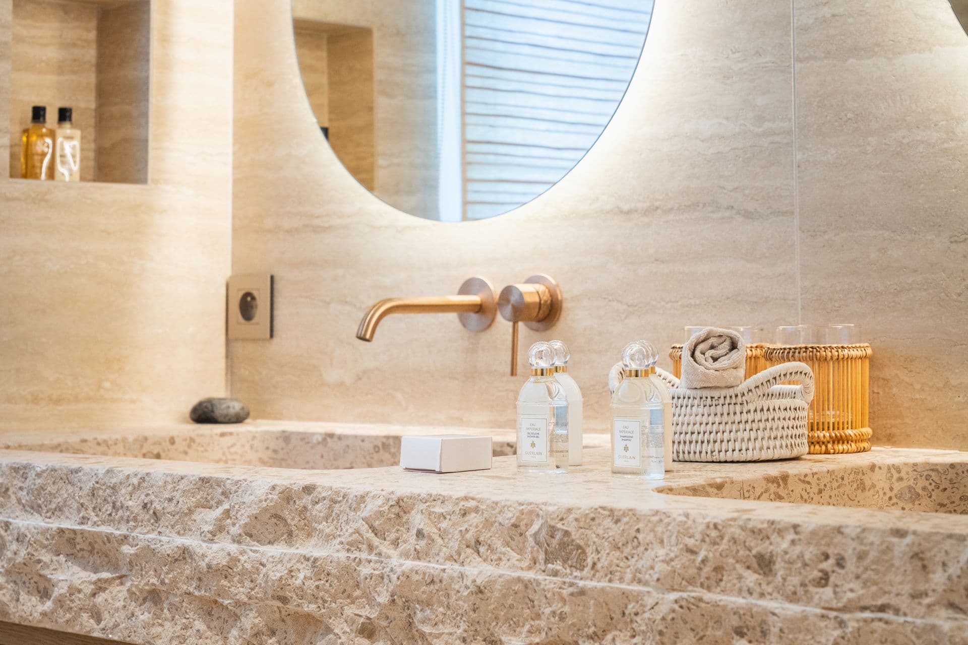 Travertine stone bathroom with a wall mounted tap and vanity display.