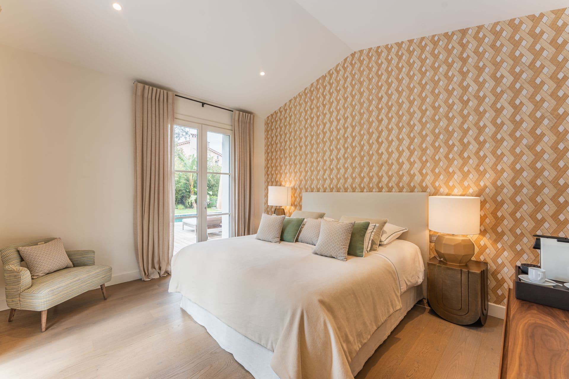 Bedroom with cream patterned wallpaper and layered white linens.