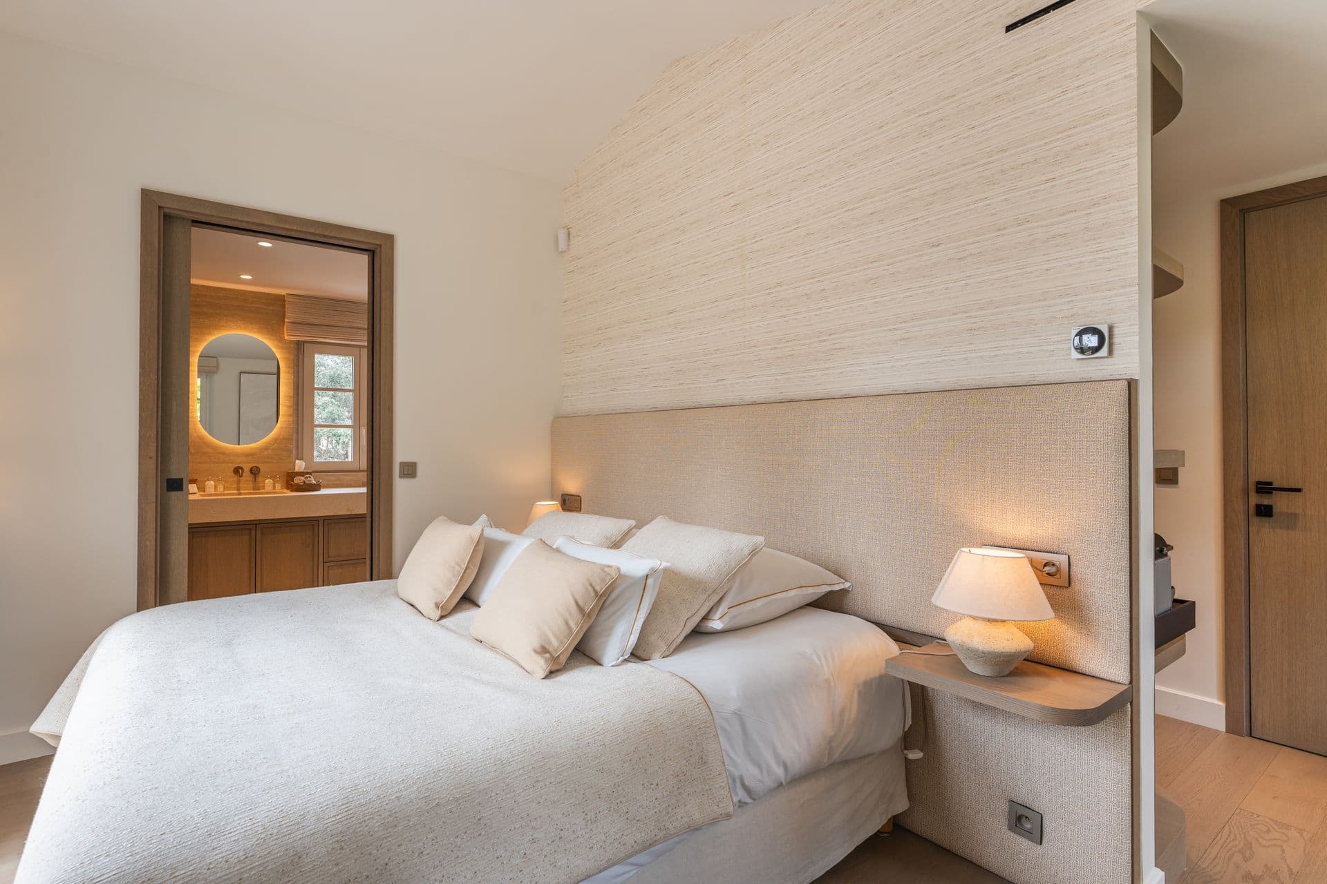 Bedroom in soft neutral tones with a woven headboard.