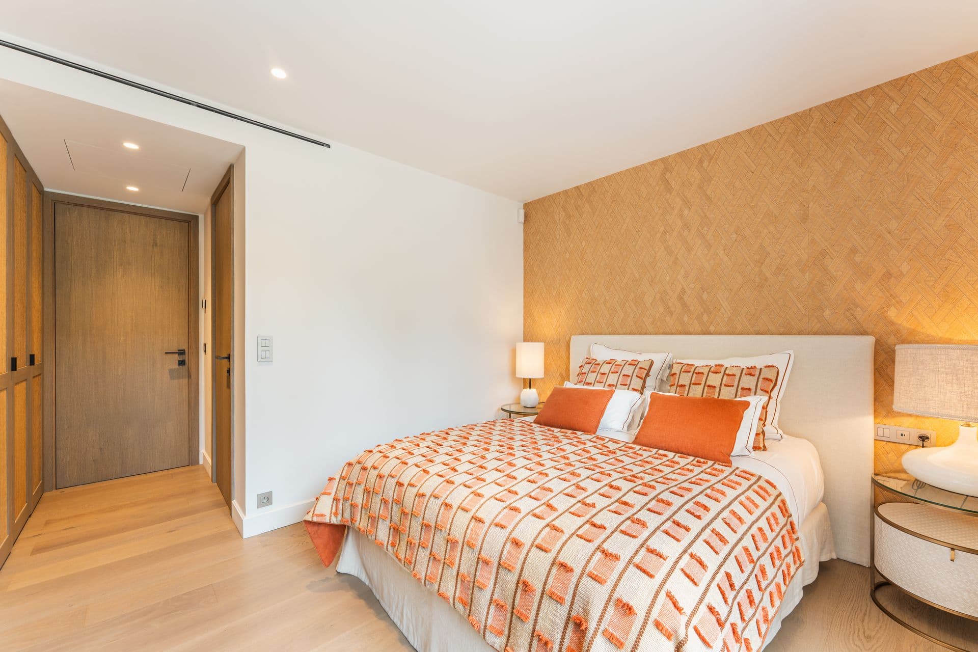 Bedroom with a geometric orange bedspread and a textured accent wall.