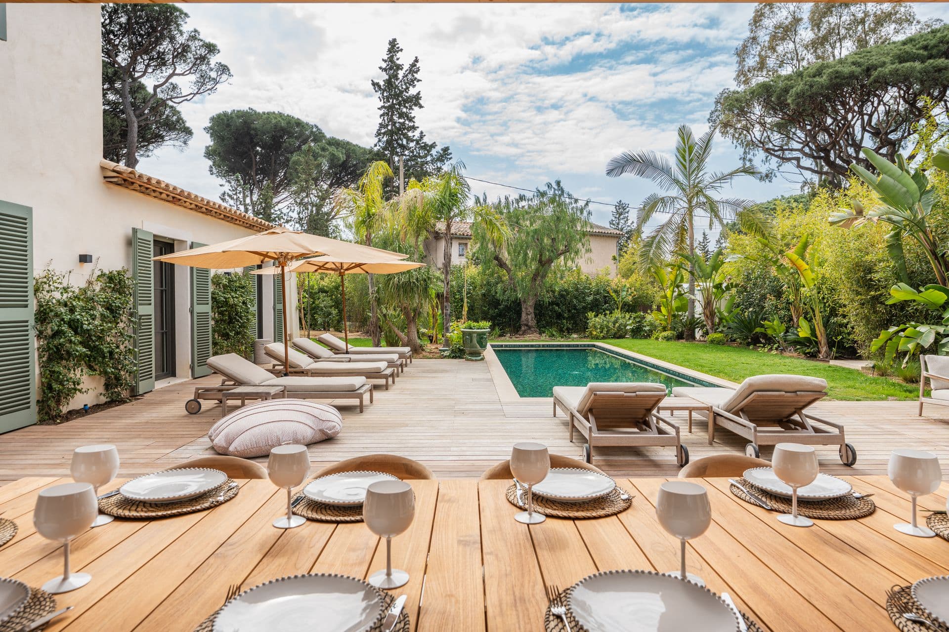 Outdoor dining deck set beneath a market umbrella among the pines.