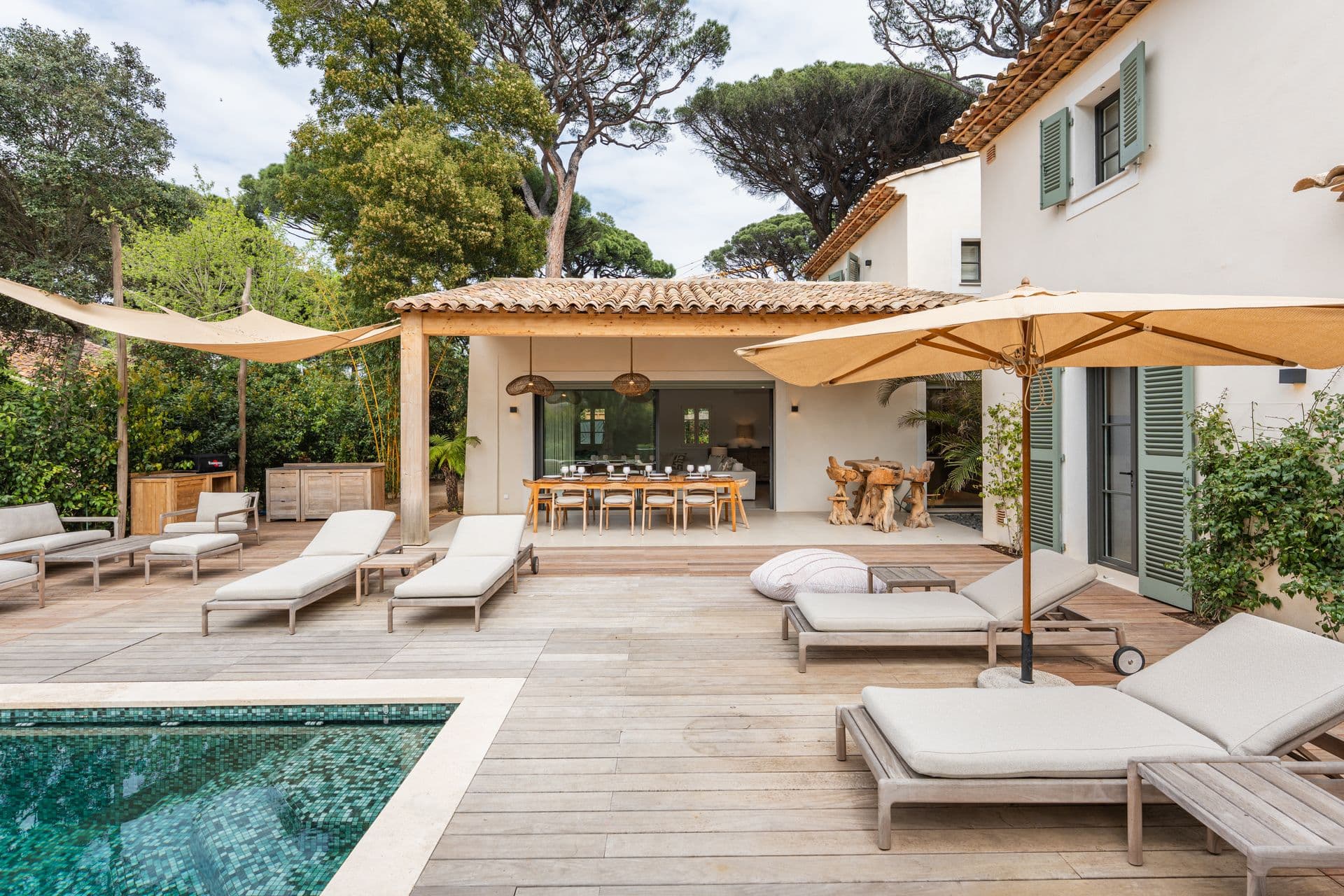 Pool and wooden deck lined with cushioned sun loungers.