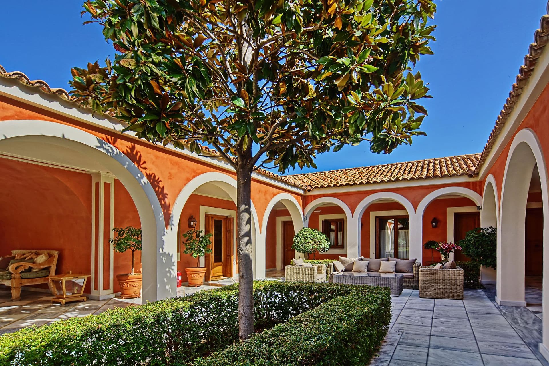 Arched colonnade wrapping the villa's inner courtyard with potted plants
