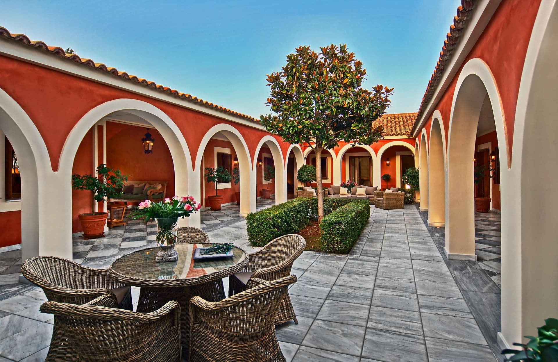 Outdoor dining table set beneath the arched courtyard loggia