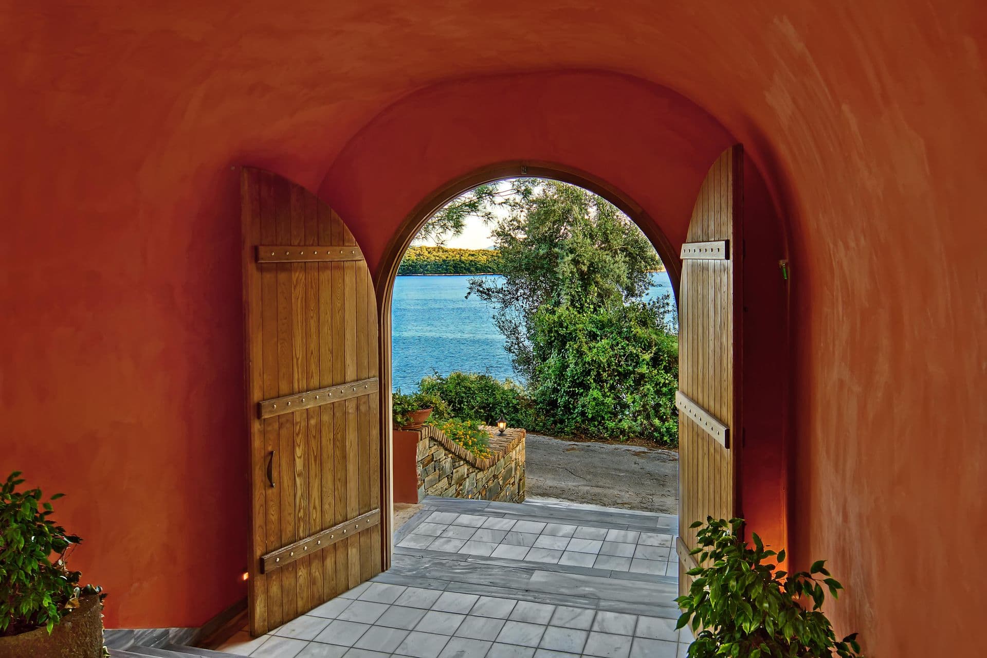 Wooden archway door framing a view of the sea from the villa grounds