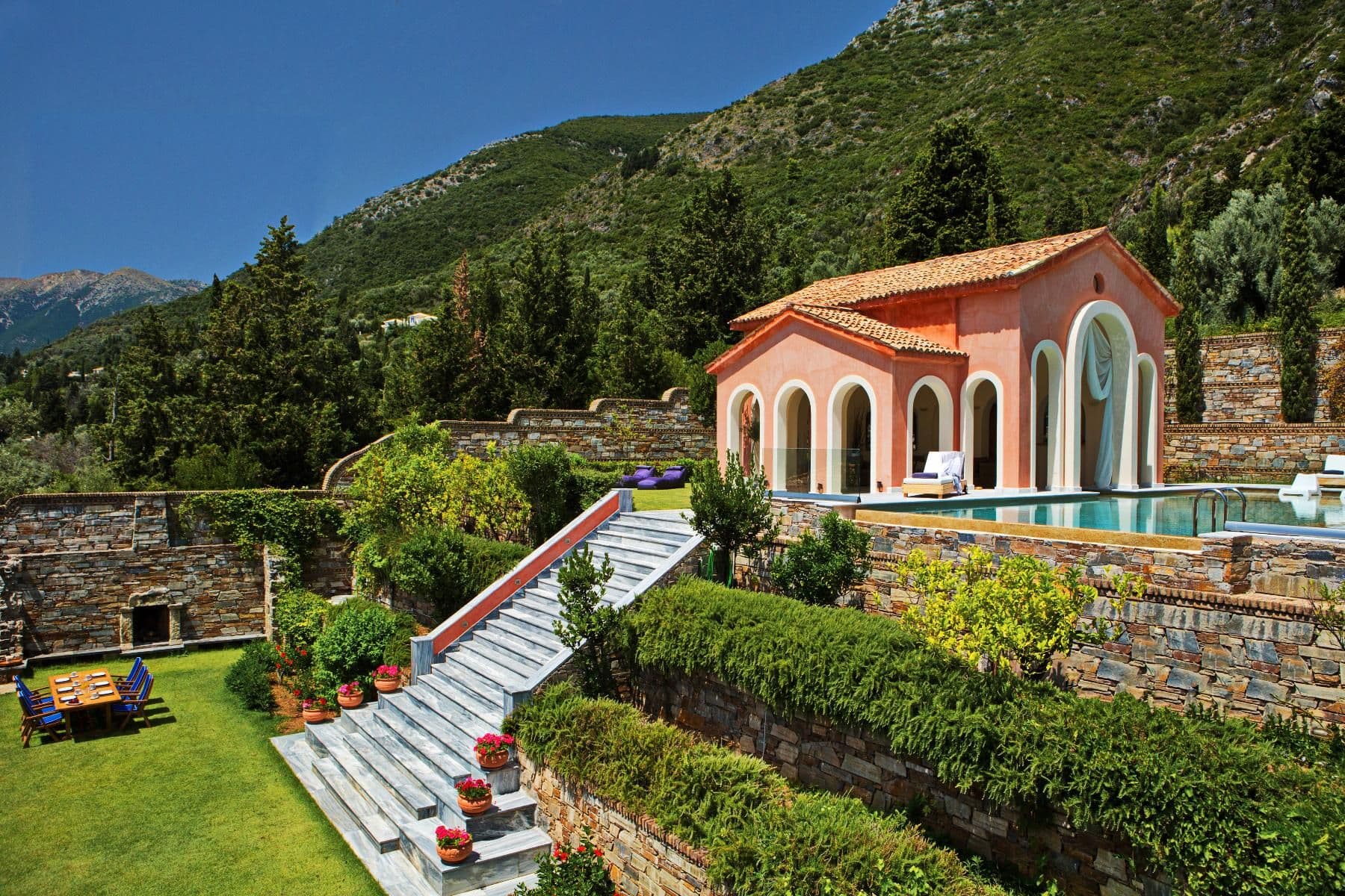 Terracotta Ionian villa with lawned terraces, cypress trees and an infinity pool overlooking the hills