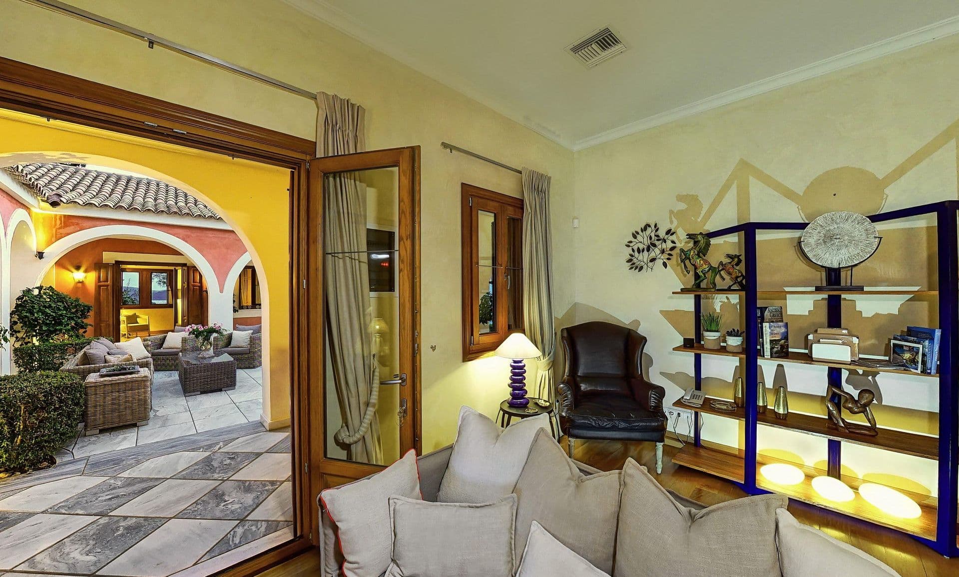 Covered arched lounge with leather armchairs and display cabinets, lit in the evening