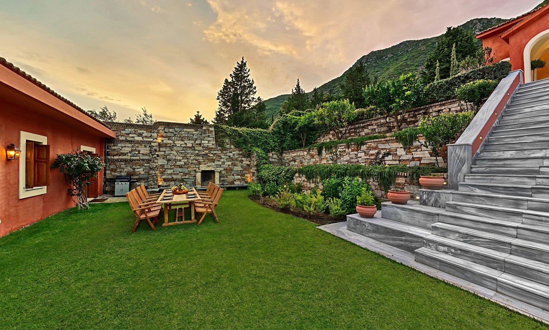Stone steps leading up a terraced lawn beside the villa at dusk