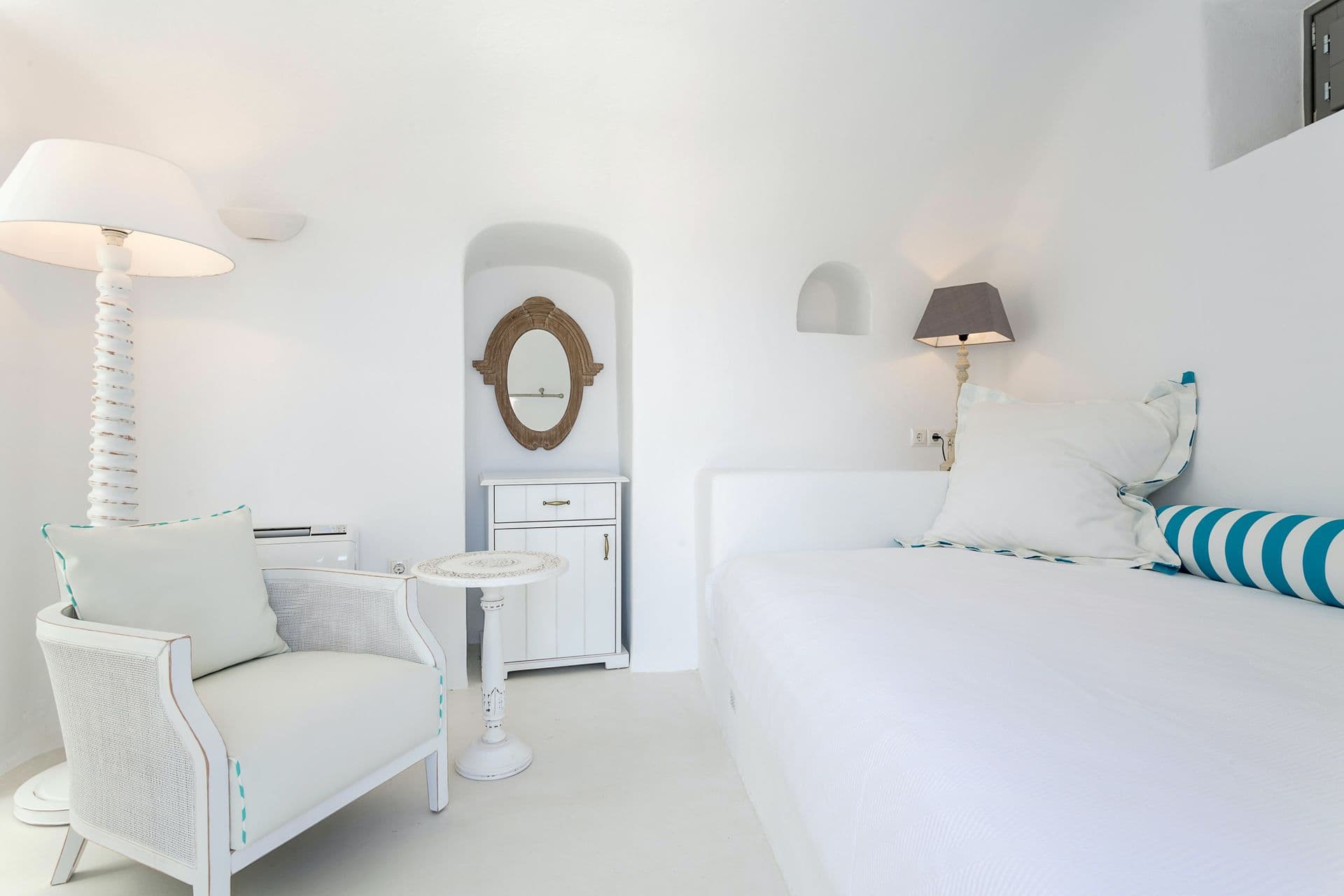 Bedroom corner with an upholstered armchair and a round mirror.