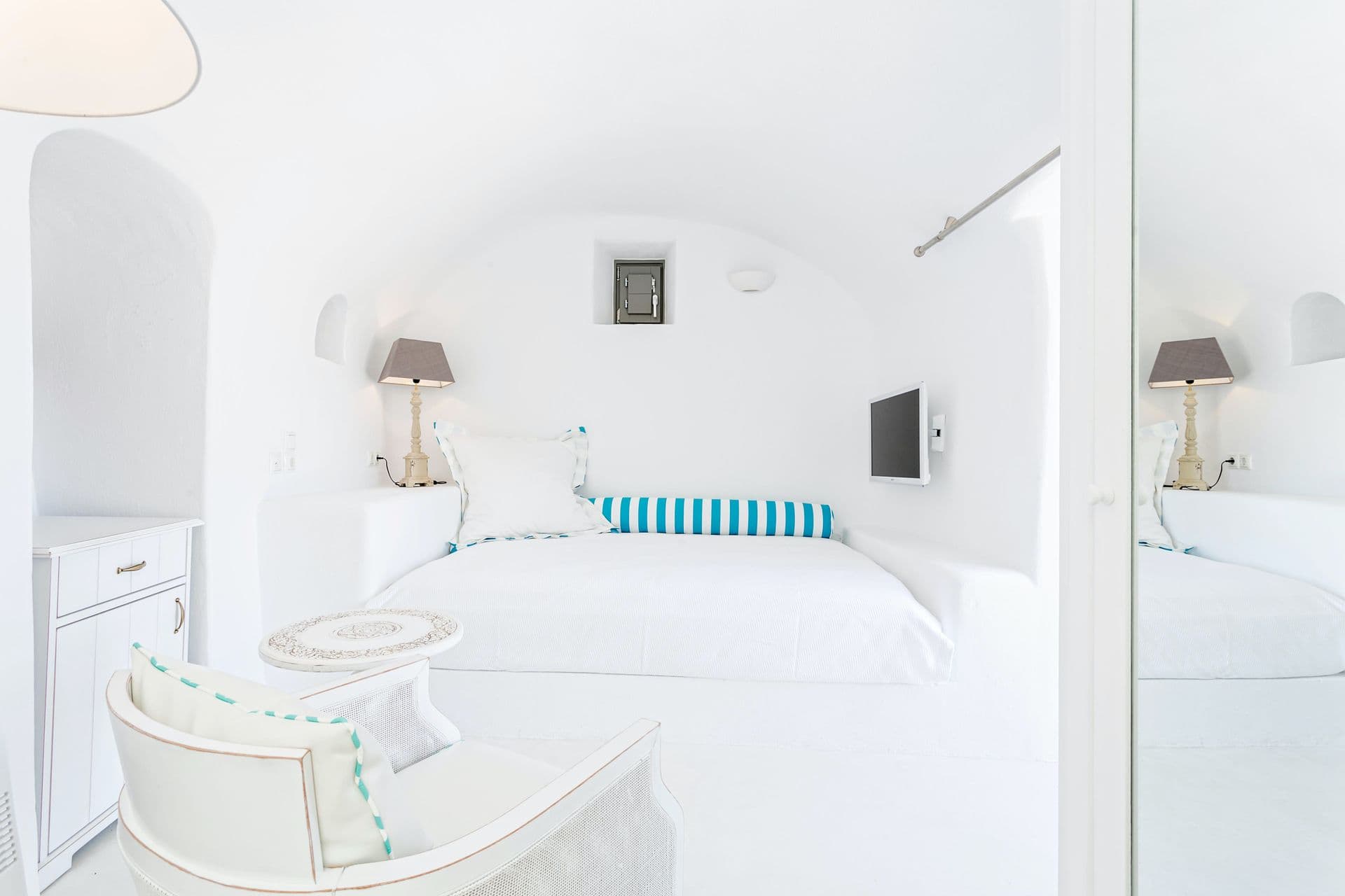 Bedroom set within a curved cave archway, styled with striped cushions.