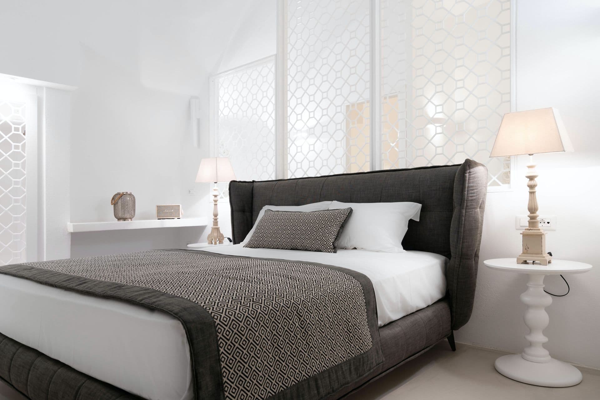 Bedroom with a tall grey upholstered headboard and bedside lamps.