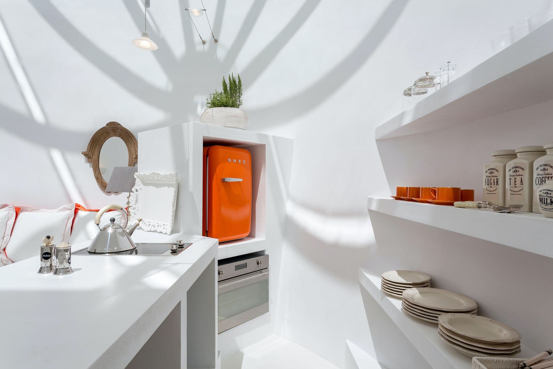 Cave style kitchen with a curved archway and a bold orange retro fridge.