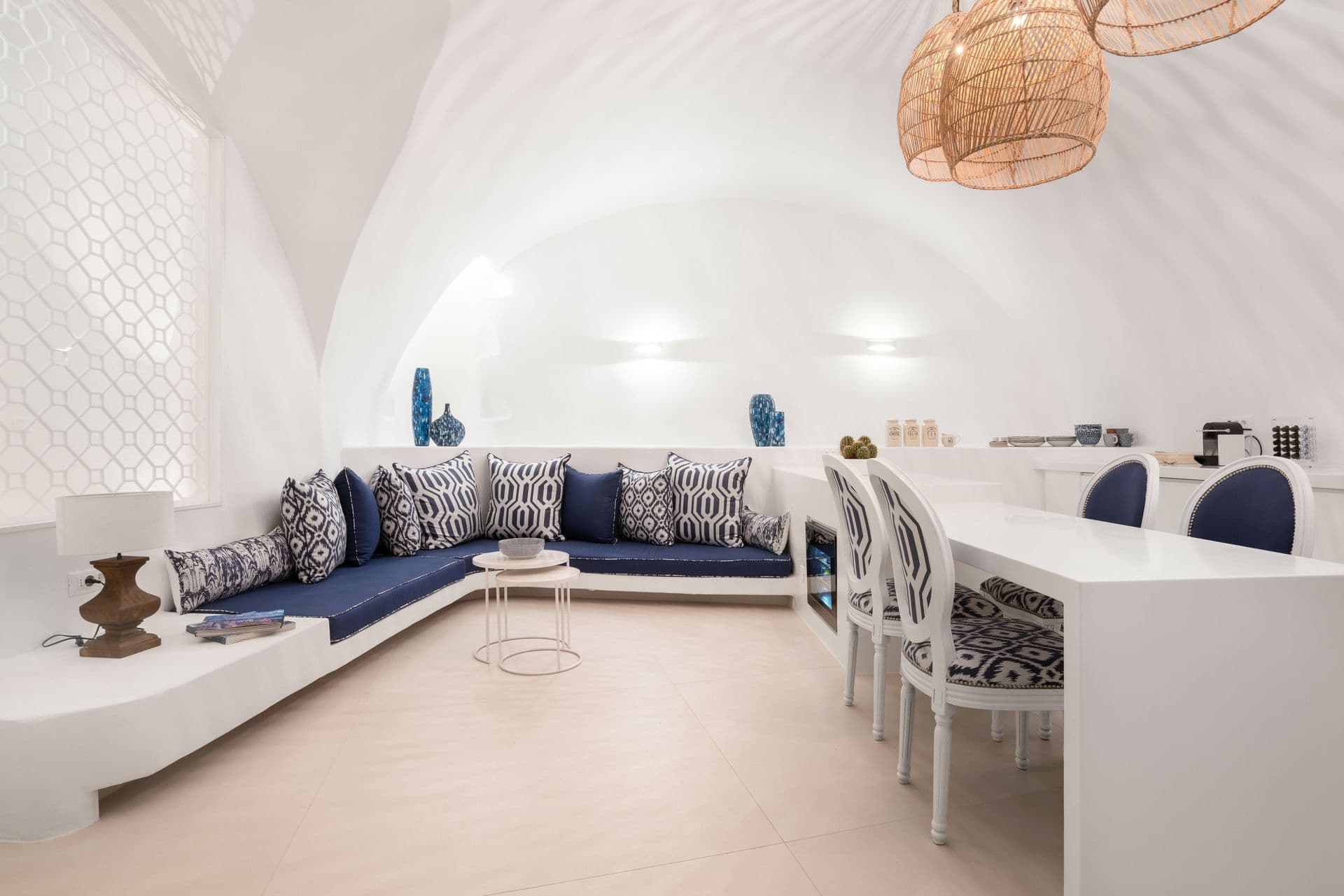 Curved banquette seating and a long dining table beneath woven pendant lights.