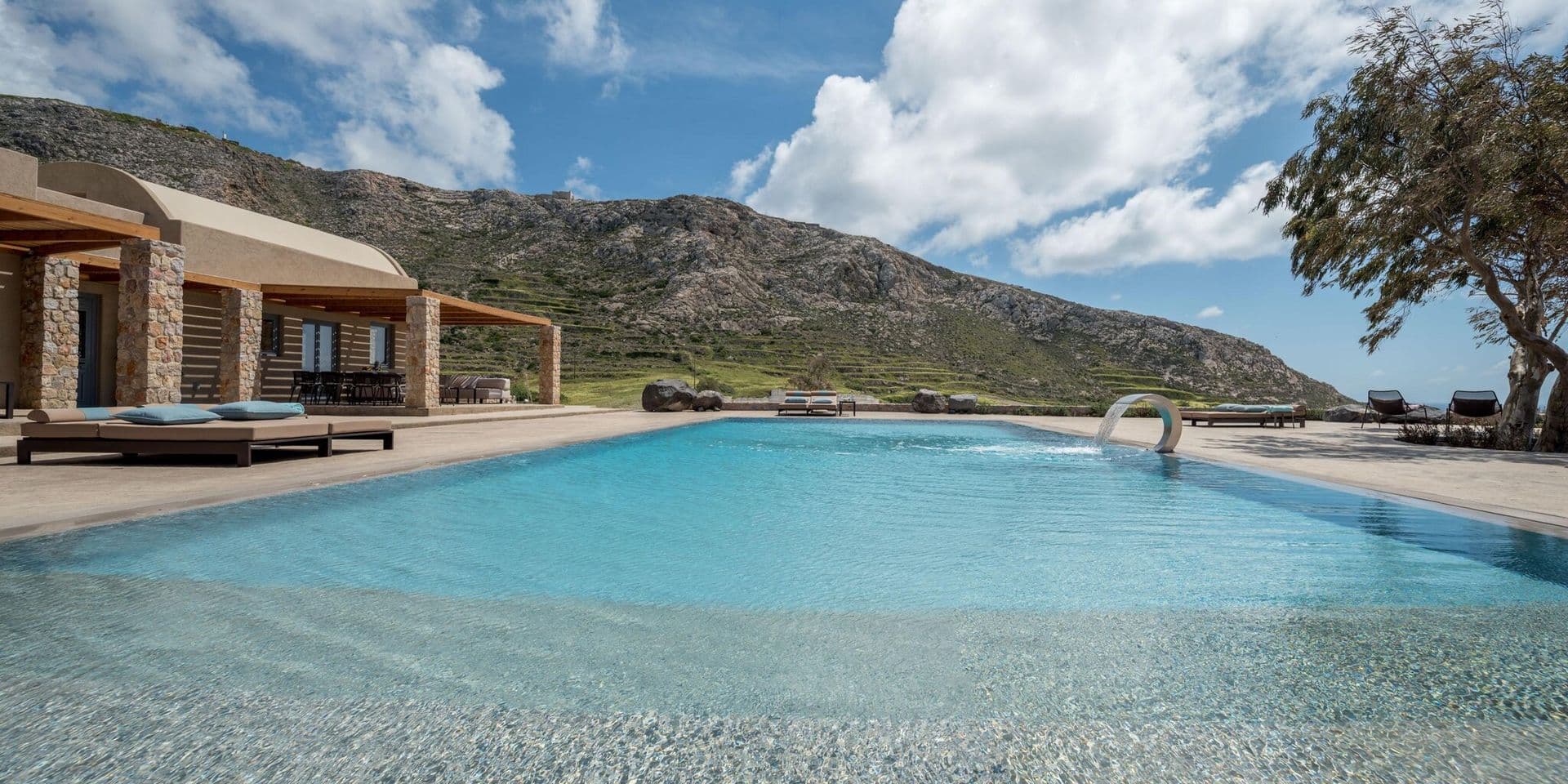 Gaia's Rest infinity pool with sun loungers, framed by the villa and hillside beyond.