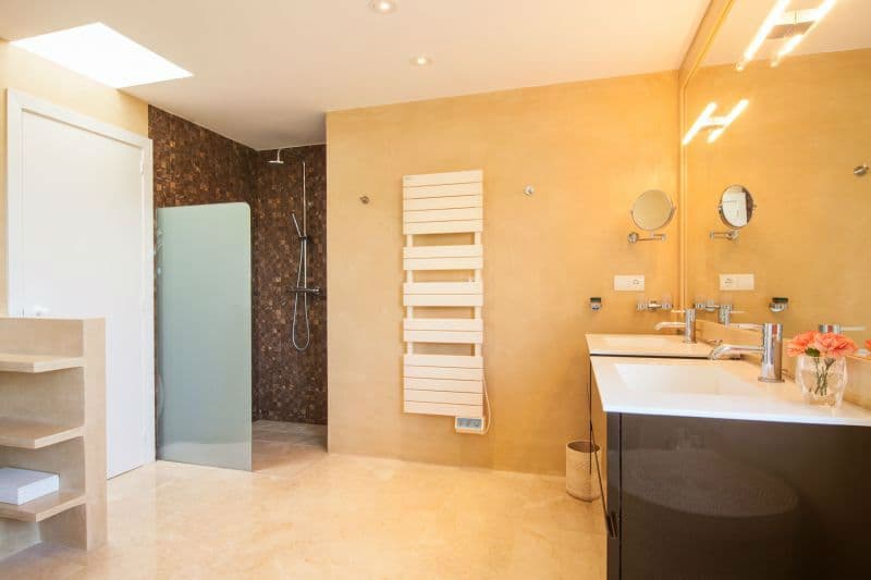 Ensuite bathroom with a glass walk in shower and warm toned tiling at Moon Kite