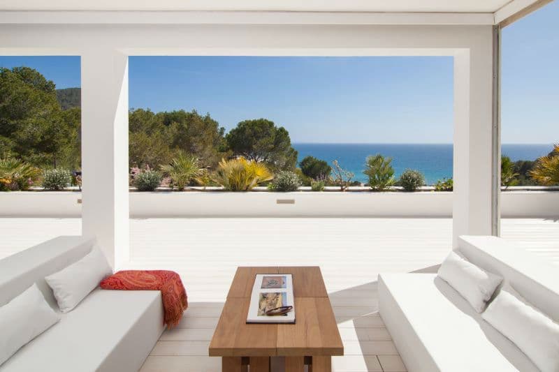White outdoor lounge seating on a covered terrace looking out to the sea at Moon Kite