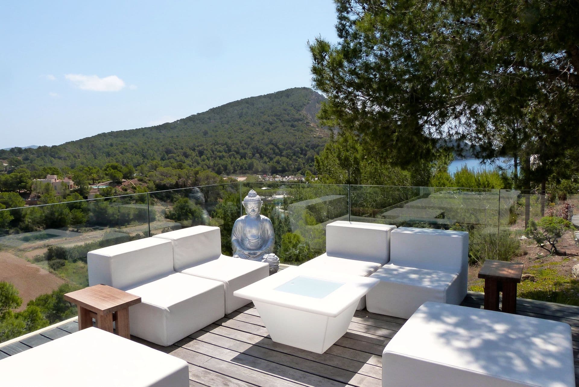 Modular white outdoor sofas around a low table with views over wooded hills at Moon Kite