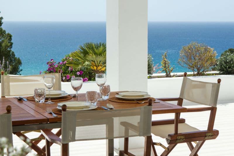 Outdoor dining table set on a terrace with the Mediterranean Sea in the distance at Moon Kite