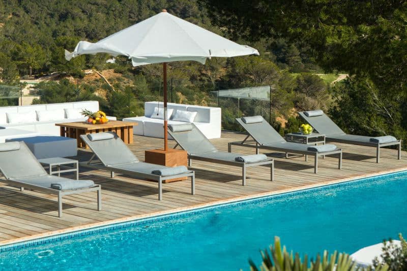 Sun loungers and a white parasol beside an infinity pool overlooking pine covered hills at Moon Kite in Ibiza