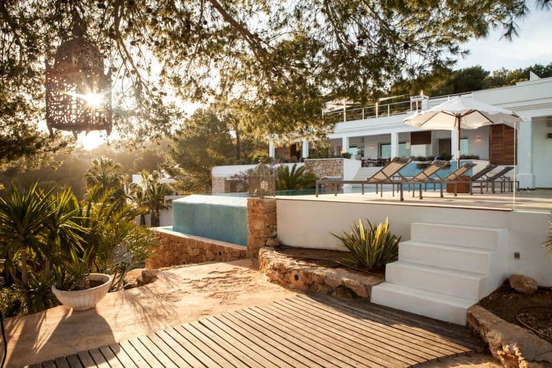 Stone terraced pool deck lit at dusk beneath the whitewashed villa at Moon Kite