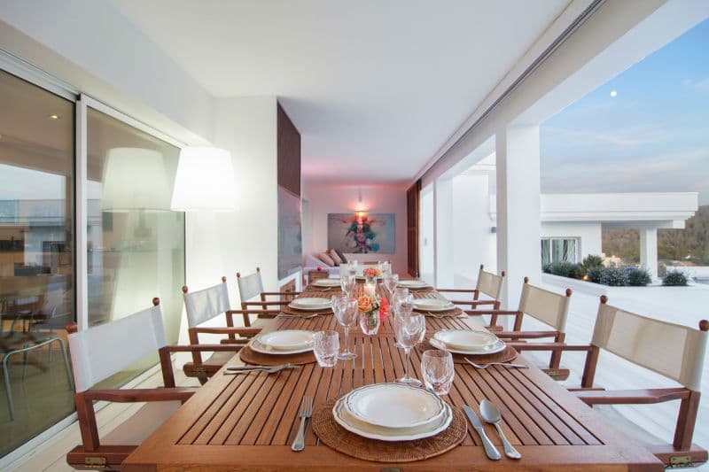 Wooden dining table set for eight beside floor to ceiling glass doors at Moon Kite