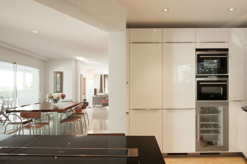Sleek white fitted kitchen opening onto a glass dining table at Moon Kite