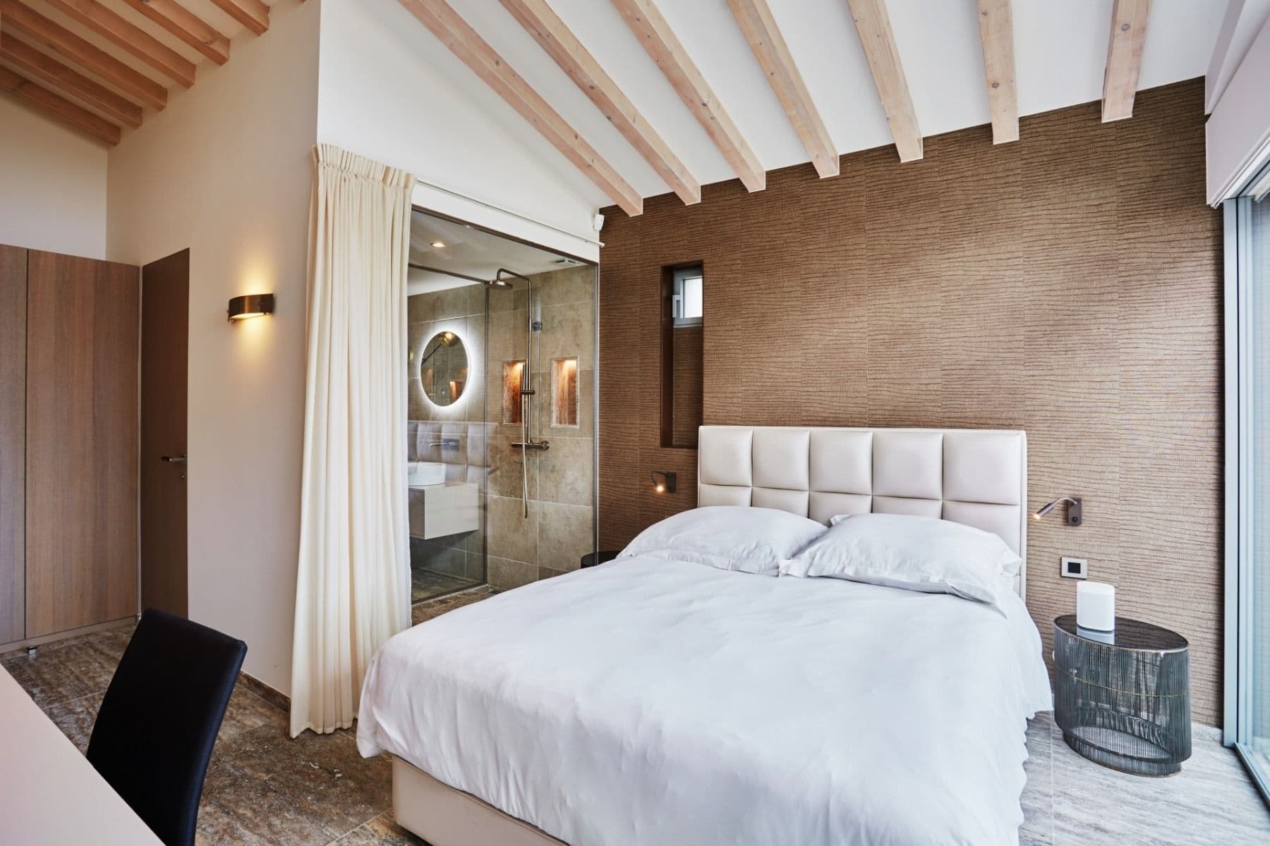Guest bedroom with exposed timber beamed ceiling and upholstered headboard