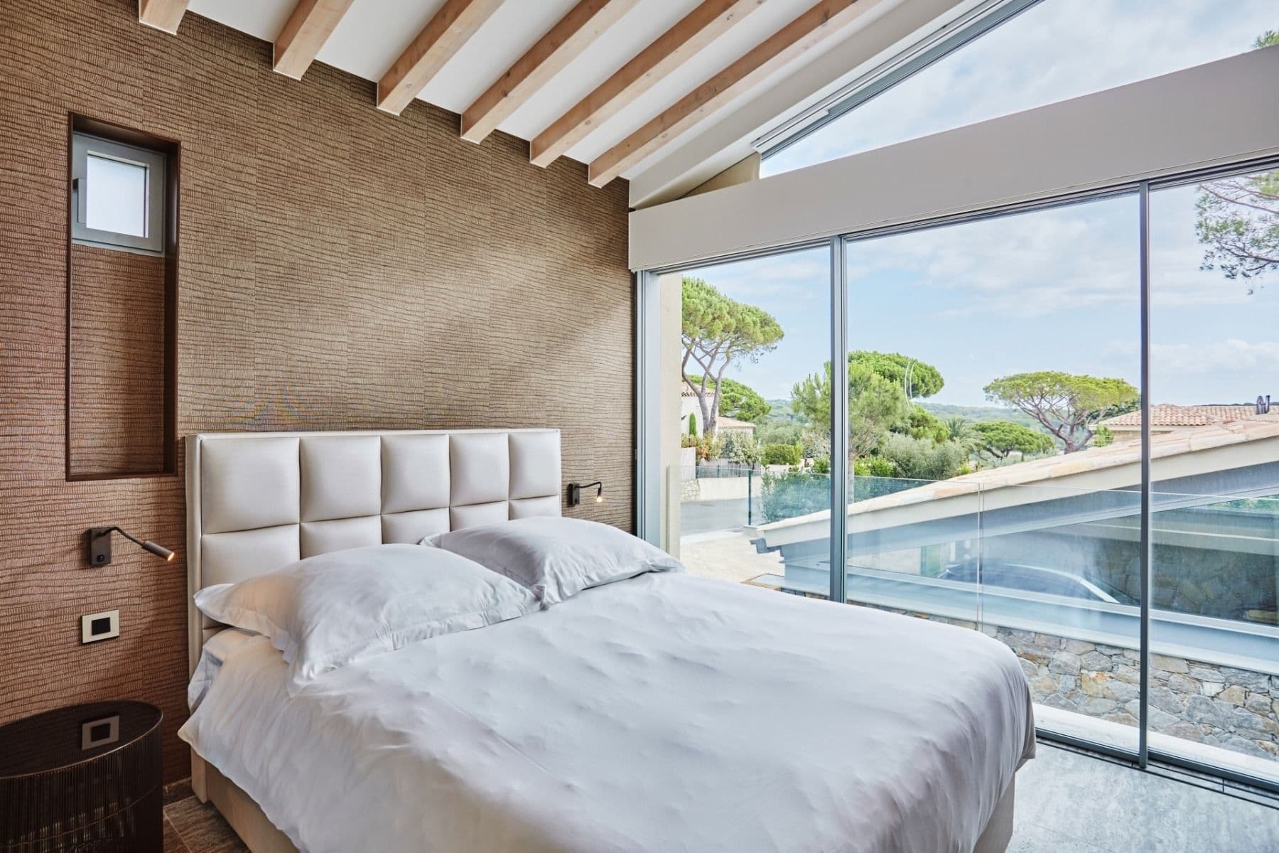 Bedroom with beamed ceiling and large window overlooking the pine garden
